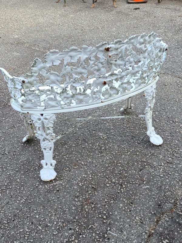 Backside view of a white antique iron bench outside