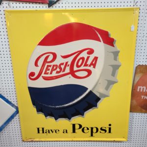Vintage yellow Pepsi Cola sign with the quote, "have a Pepsi" written on the bottom